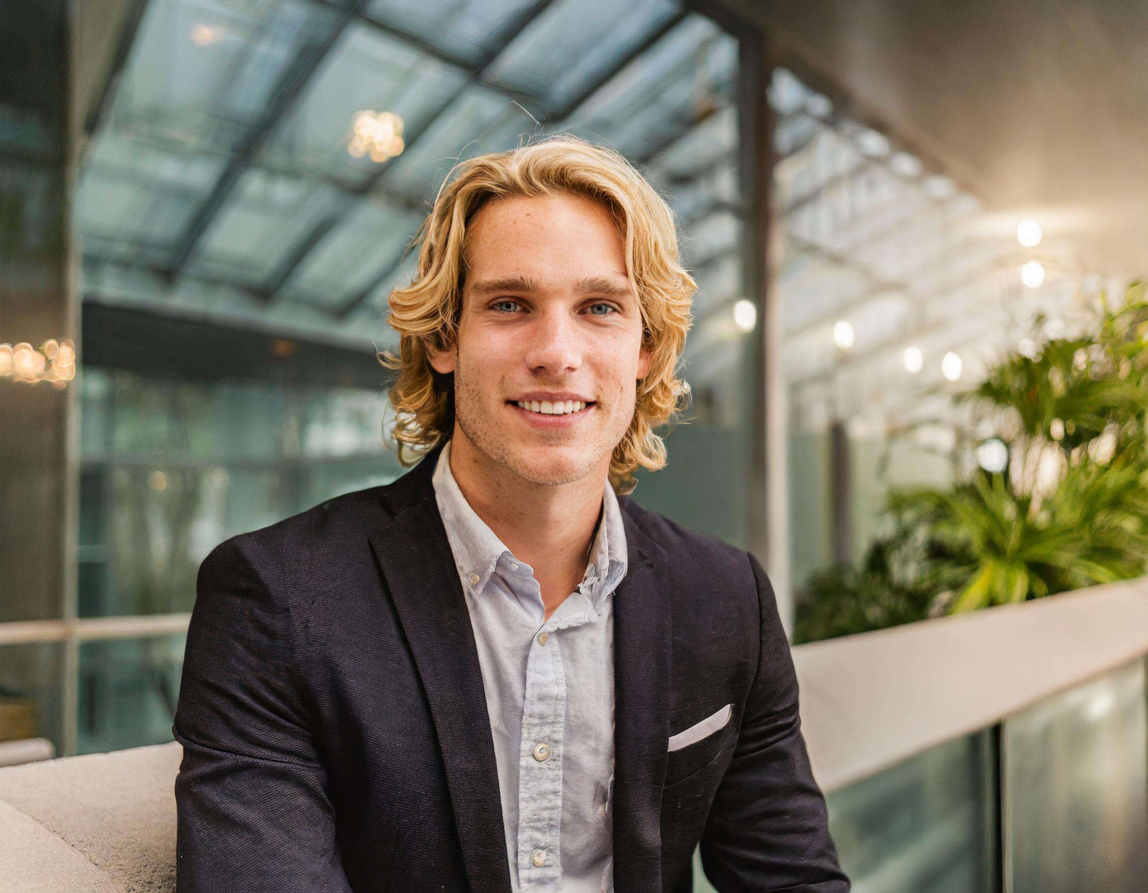 Porträt eines jungen Mannes, sympathisch lächelnd, mit stilvollem Haarschnitt